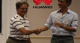 Two men shaking hands in front of a huawei logo.