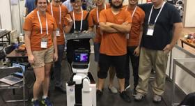 A group of people posing with a robot.