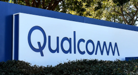 A sign for qualcomm is shown in front of bushes.