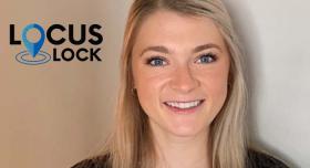 A woman smiling in front of a wall with the logo locus lock.