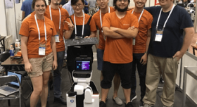 A group of people posing for a picture in front of a robot.
