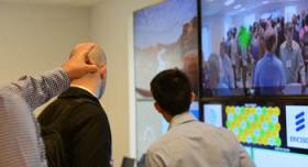 A group of people looking at several monitors in a room.
