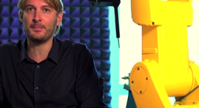 A man sitting in front of a yellow robot.