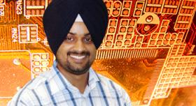A man in a turban standing in front of a circuit board.
