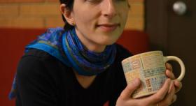 A woman with a scarf holding a coffee mug.
