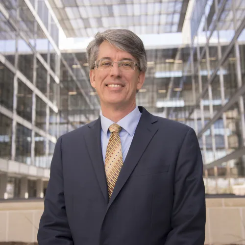 Man smiling in front of building.
