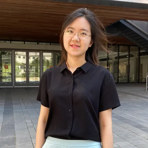 Woman smiling in front of building.