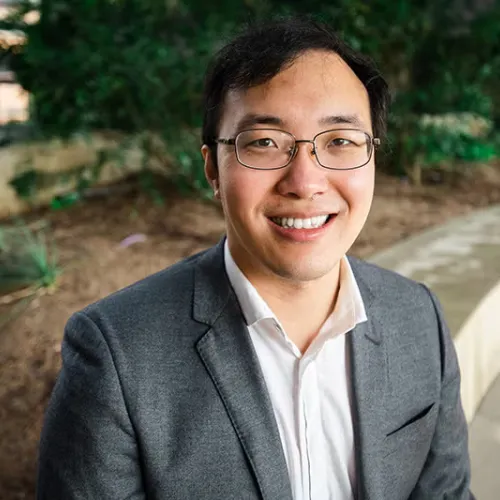 Man with glasses smiling.