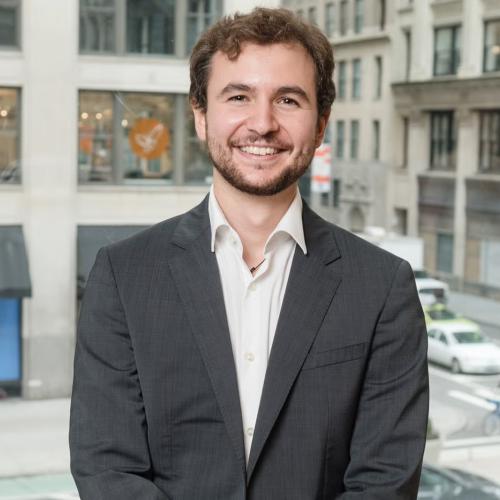 Man in blazer in front of building.