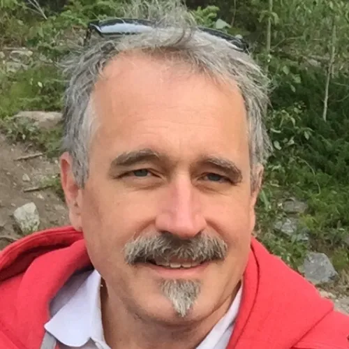 A man in a red hoodie with a mustache.