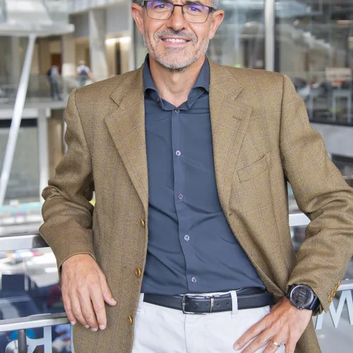 A man wearing glasses and a tan jacket.