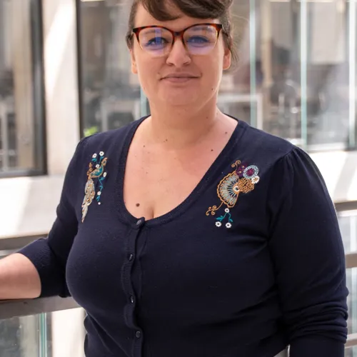 A woman in glasses standing on a railing.