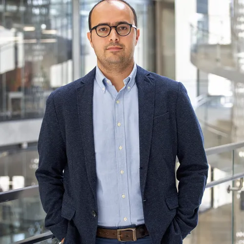 A man in glasses standing in front of a building.